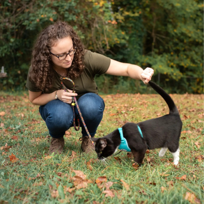 woman with cat outside on a harness and leash
